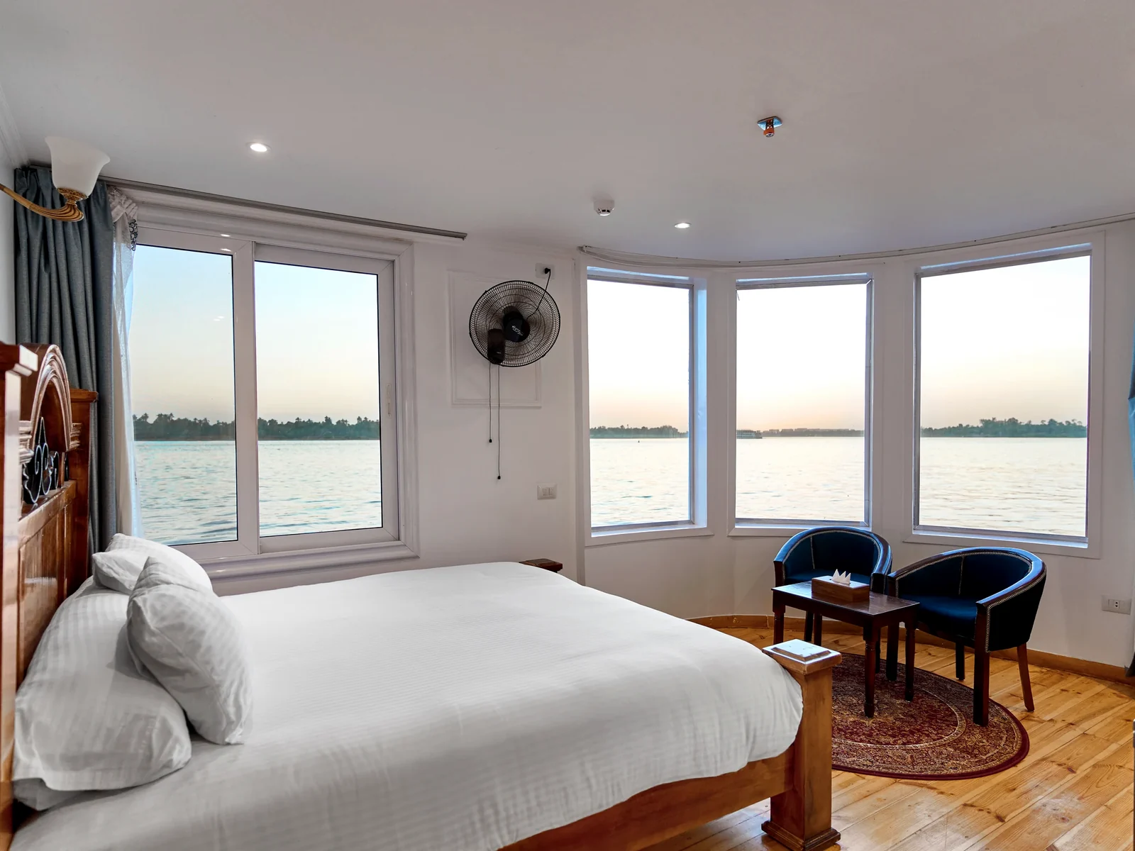Panoramic suite with king bed and wide Nile windows aboard Fatima Dahabeya