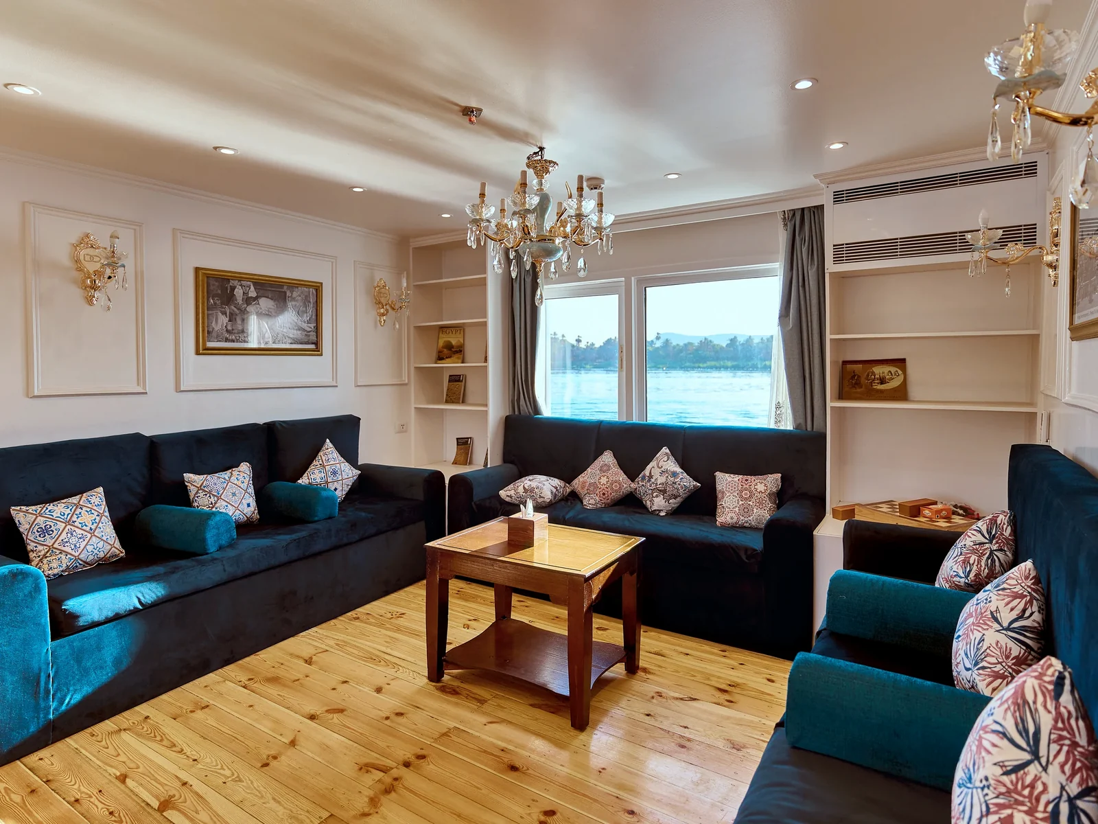 Salon interior aboard Fatima Dahabeya with blue seating and Nile windows